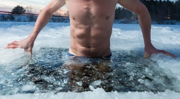 Man lowering himself into an icy lake