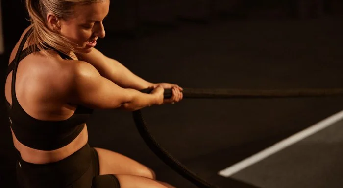 Woman training with battle ropes in a dimly lit gym