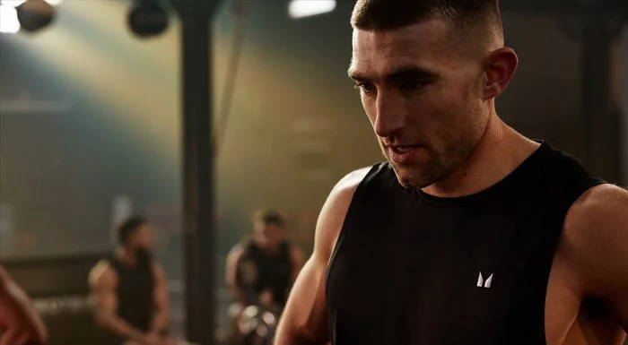 Man in a black Myprotein vest training in a busy gym