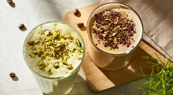 Two protein shakes topped with chopped pistachios and chocolate