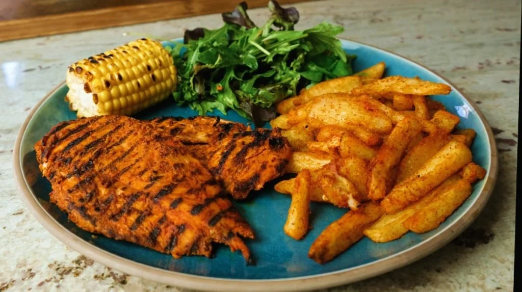 Peri peri chicken breast with potato wedges, corn on the cob and salad