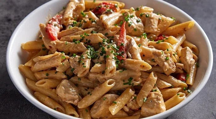 Bowl of creamy Cajun chicken penne pasta with peppers and chives