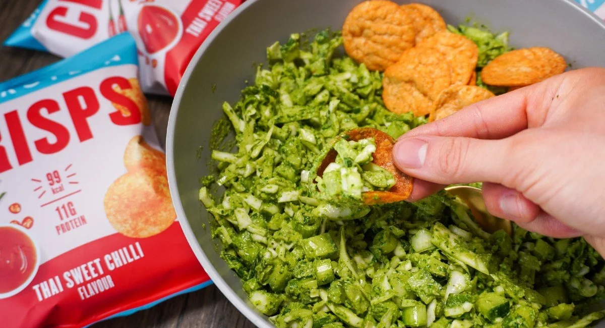 Hand scooping green goddess salad with a Myprotein protein crisp