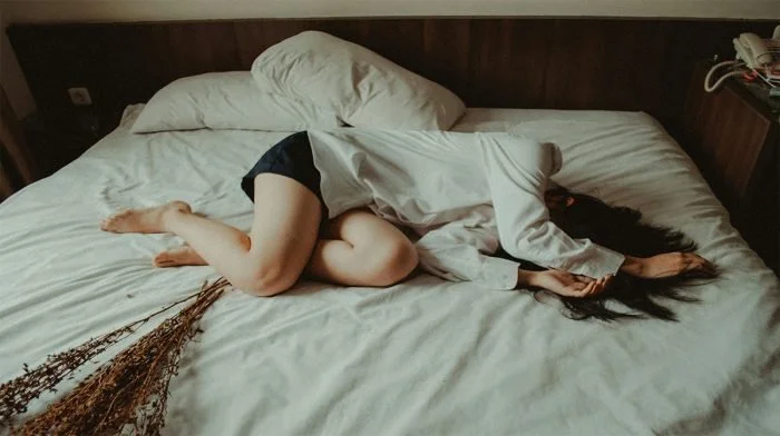 Woman lying asleep across a bed