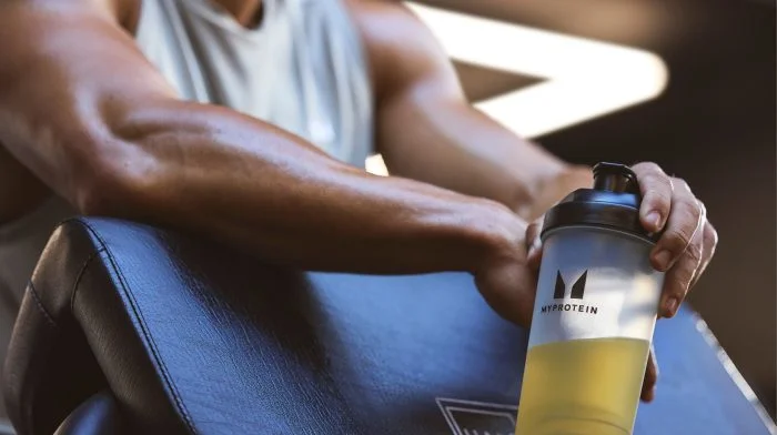 Man on a gym bench holding a Myprotein shaker
