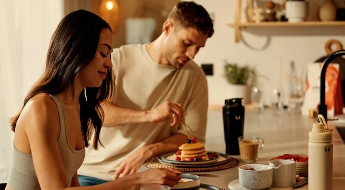Couple eating pancakes at a kitchen table