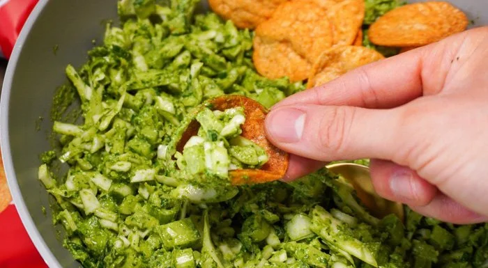 Green goddess salad being scooped up with a tortilla chip