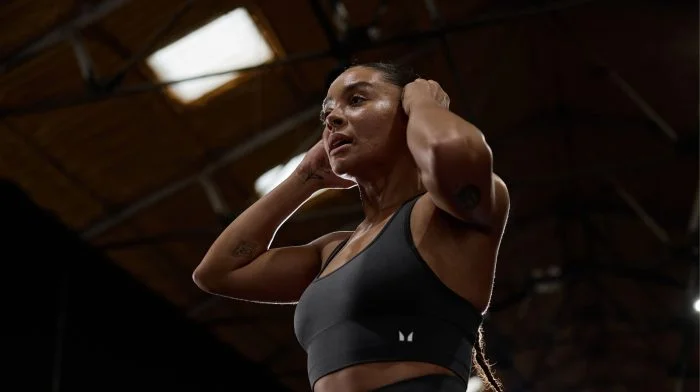 Woman in a sports bra catching her breath in the gym