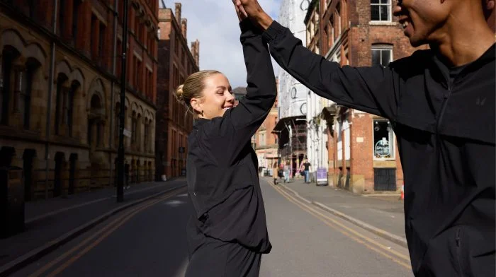 Two runners high-fiving on a city street