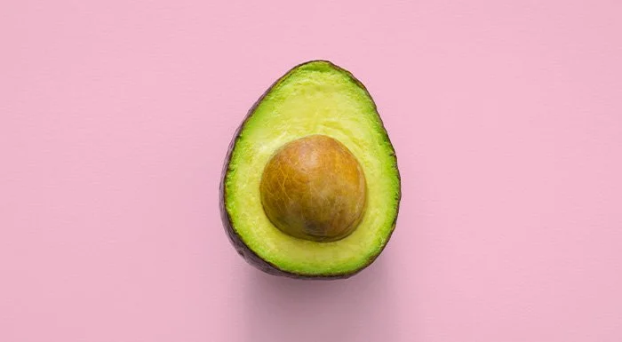 Halved avocado on a pink background