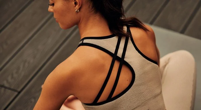 Woman in a sports bra sitting on the floor, seen from behind
