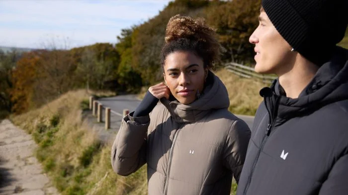 Man and woman in Myprotein puffer jackets on a countryside walk
