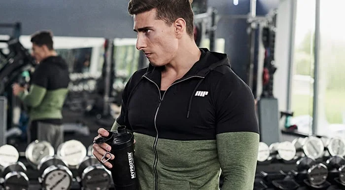 Man in a Myprotein hoodie holding a shaker in the gym