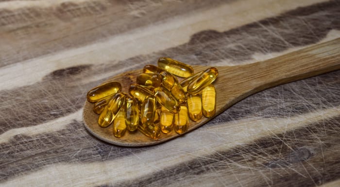 Omega-3 fish oil capsules on a wooden spoon