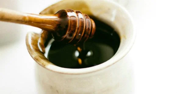 Honey dipper in a pot of dark agave syrup