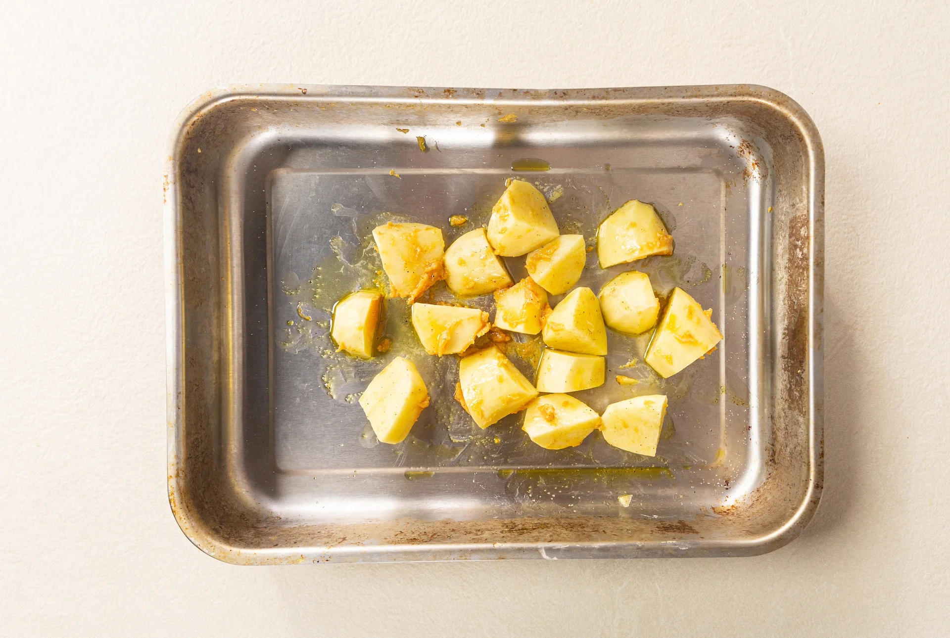 Chopped potatoes on a greased tray coated in miso paste.