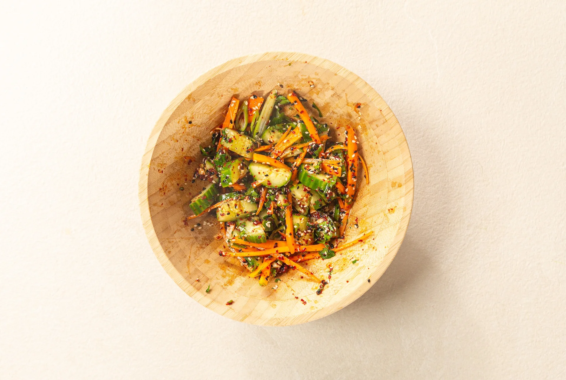 Cucumber, carrot, spices and sesame mixed in a bowl.
