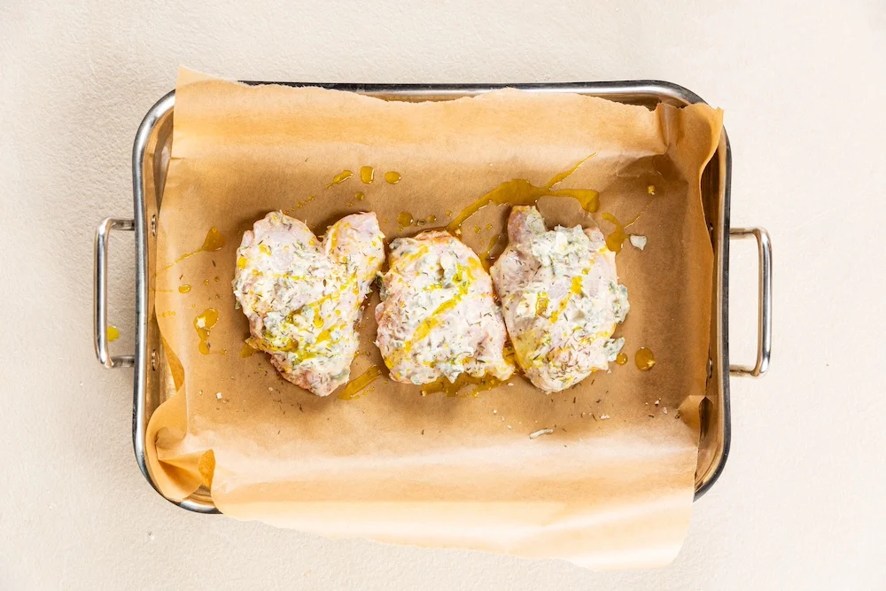 Chicken placed on a greaseproof tray covered in the yoghurt coating.