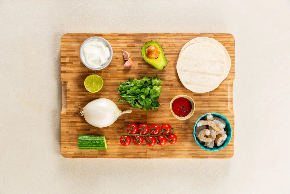 Ingredients for prawn tacos laid out on a chopping board.