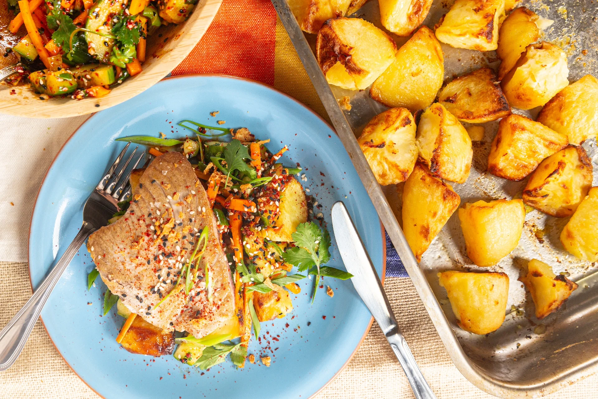 Tuna steak on a bed of roasted potatoes and salad.