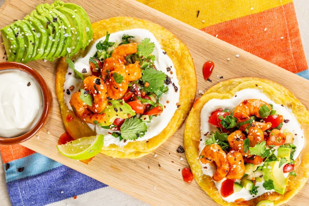 Two tortilla wraps topped with prawns, dressing, and tomatoes.