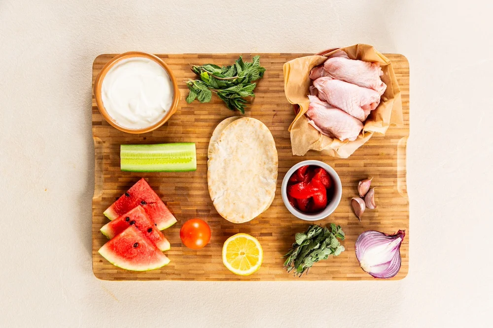 Ingredients for Chicken Tzatziki Pita laid on a chopping board.