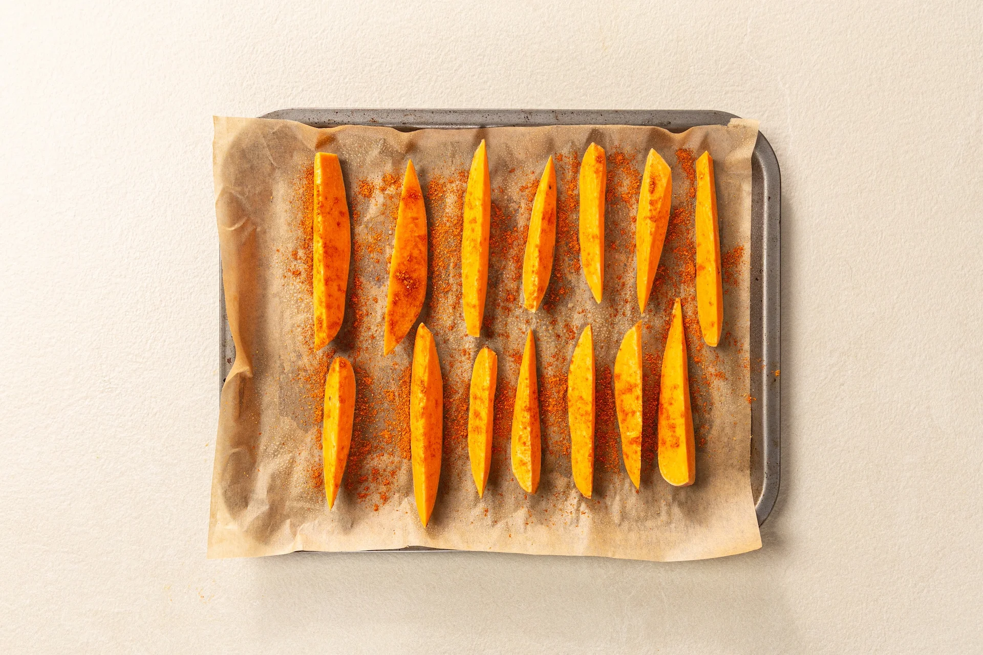 Potatoes wedges cut on a lined baking tray.
